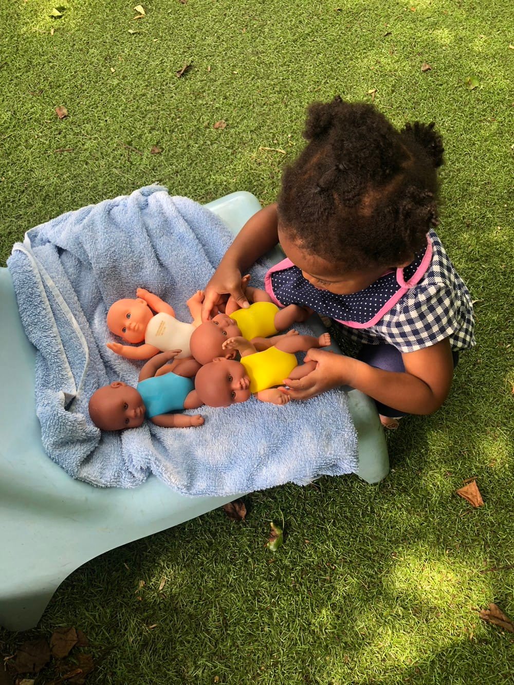 young child playing with baby dolls outside